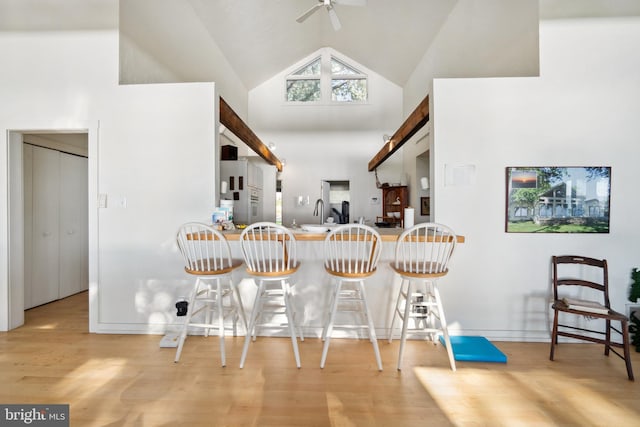 kitchen featuring light hardwood / wood-style floors, high vaulted ceiling, a kitchen bar, and ceiling fan