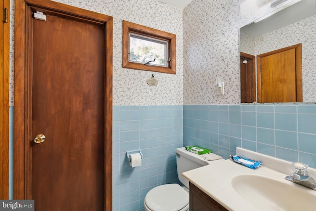 bathroom with tile walls, vanity, and toilet