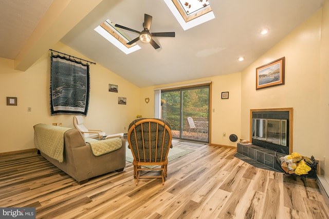 living room with light wood-type flooring, lofted ceiling, ceiling fan, and a fireplace