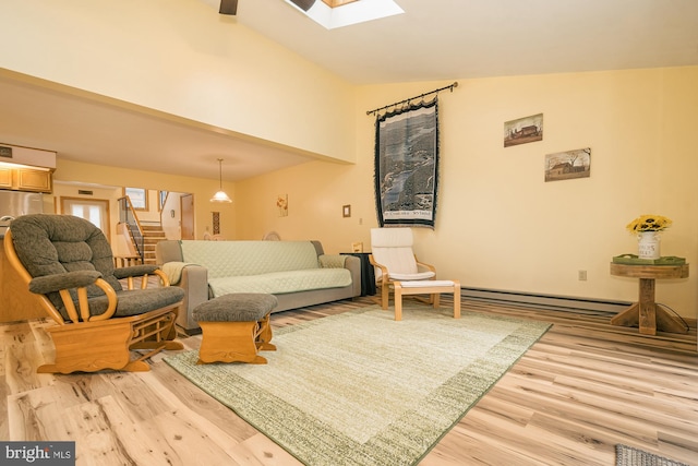 living room featuring lofted ceiling with skylight, hardwood / wood-style floors, and a baseboard heating unit