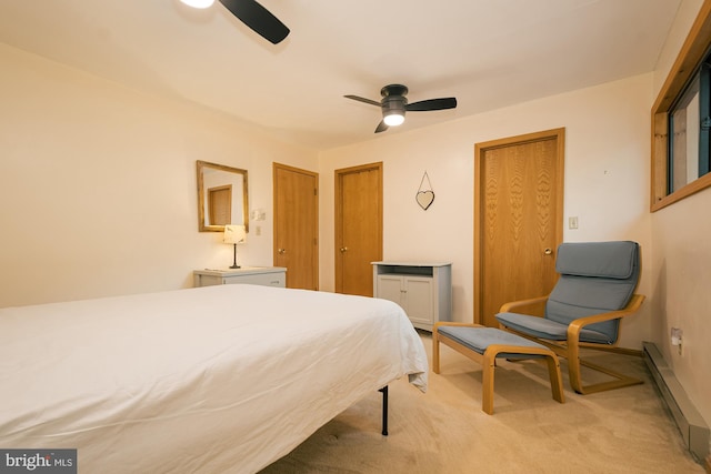 carpeted bedroom featuring a baseboard heating unit, two closets, and ceiling fan