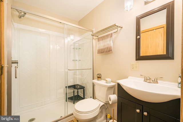 bathroom featuring a shower with door, vanity, and toilet