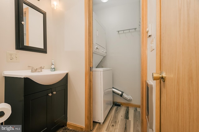 bathroom with wood-type flooring, vanity, and stacked washer and clothes dryer