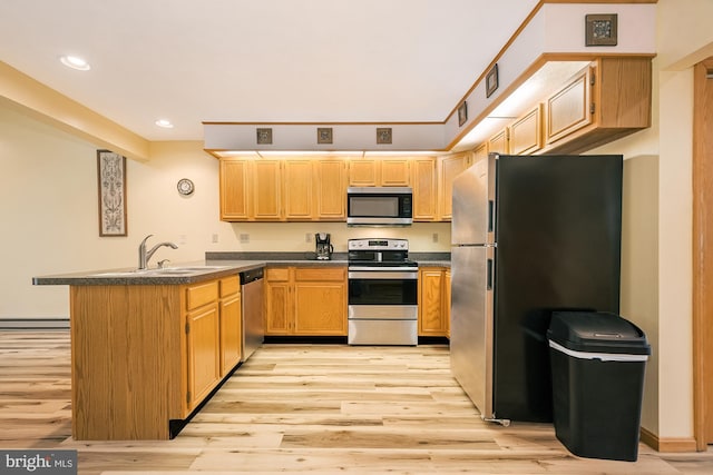 kitchen featuring appliances with stainless steel finishes, light wood-type flooring, sink, and kitchen peninsula