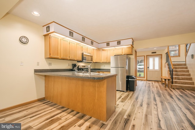 kitchen featuring light brown cabinetry, stainless steel appliances, light wood-type flooring, and kitchen peninsula