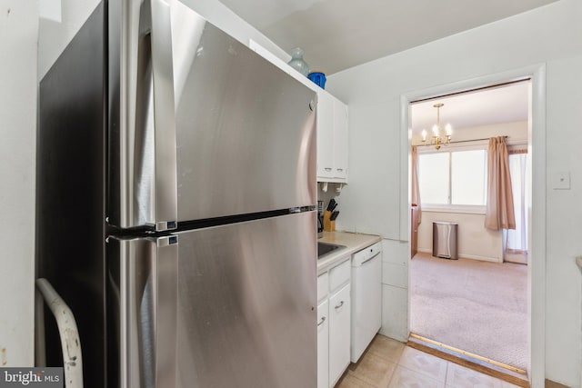 kitchen featuring white cabinetry, a chandelier, white dishwasher, and stainless steel refrigerator