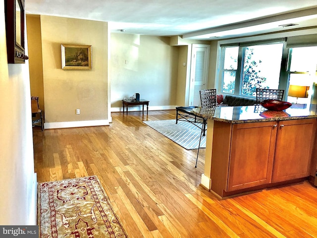 kitchen with light hardwood / wood-style floors and dark stone countertops