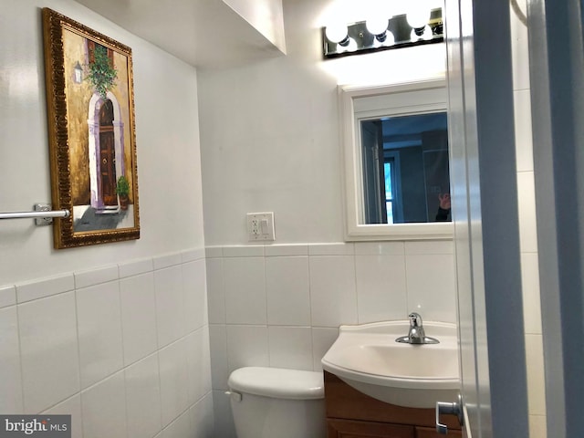 bathroom with vanity, toilet, and tile walls