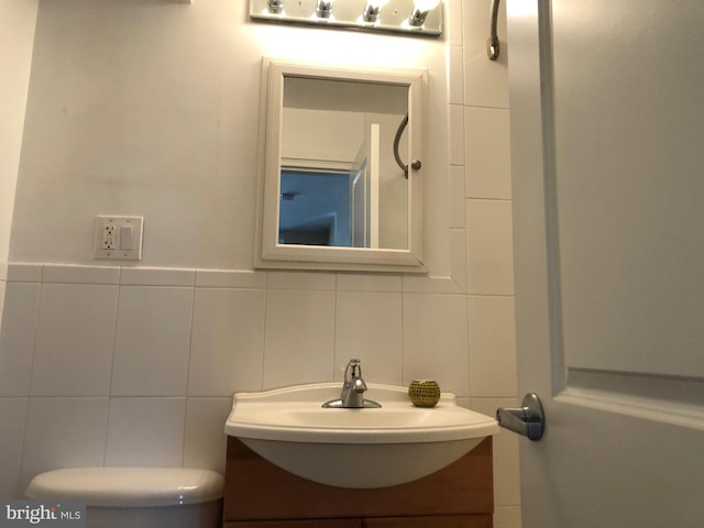 bathroom with vanity, tasteful backsplash, toilet, and tile walls