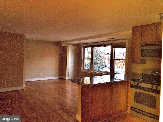 kitchen with white gas range oven, kitchen peninsula, and hardwood / wood-style floors