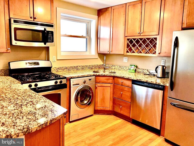 4840 Macarthur Blvd NW Unit 501, Washington, DC 20007 - kitchen with a sink, washer / clothes dryer, stainless steel appliances, light stone counters, and light wood-style flooring