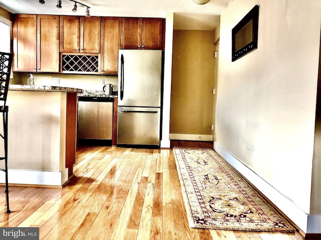 kitchen featuring stone counters, appliances with stainless steel finishes, and light wood-type flooring