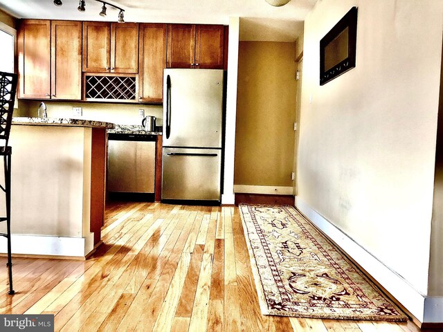 4840 Macarthur Blvd NW Unit 501, Washington, DC 20007 - kitchen with brown cabinets, light wood-style flooring, baseboards, and appliances with stainless steel finishes