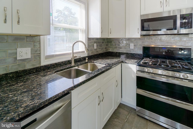 kitchen featuring appliances with stainless steel finishes, sink, backsplash, dark stone counters, and white cabinets