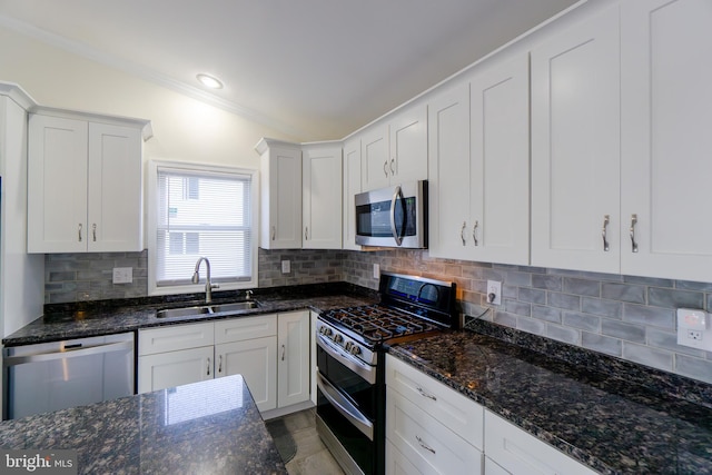 kitchen featuring appliances with stainless steel finishes, white cabinets, sink, and dark stone counters