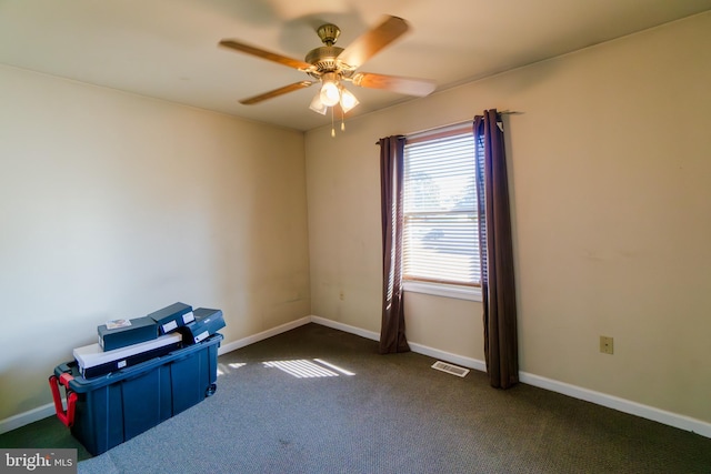 empty room with dark colored carpet and ceiling fan