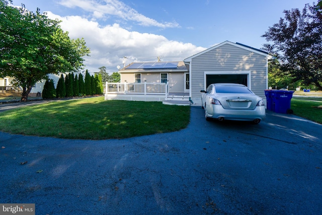 ranch-style home featuring a garage, a front lawn, and solar panels