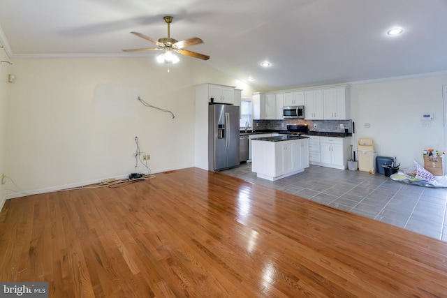 kitchen with dark hardwood / wood-style floors, stainless steel appliances, a center island, vaulted ceiling, and white cabinets