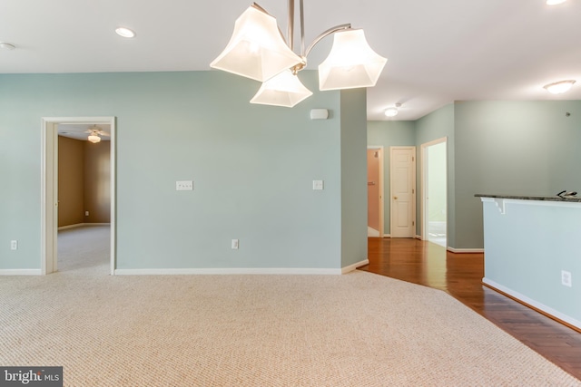 unfurnished room with ceiling fan with notable chandelier and dark hardwood / wood-style flooring