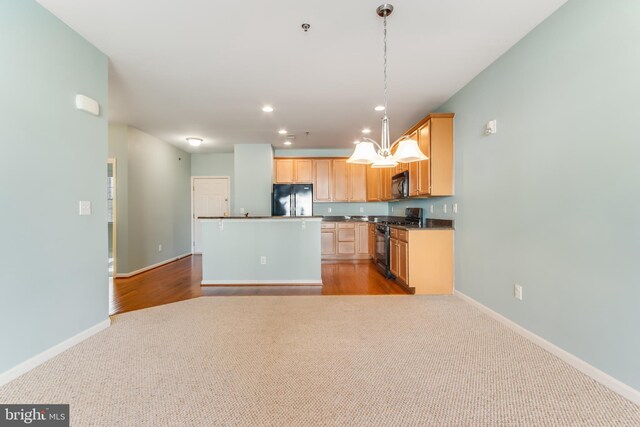 kitchen featuring light brown cabinetry, pendant lighting, light carpet, and black appliances