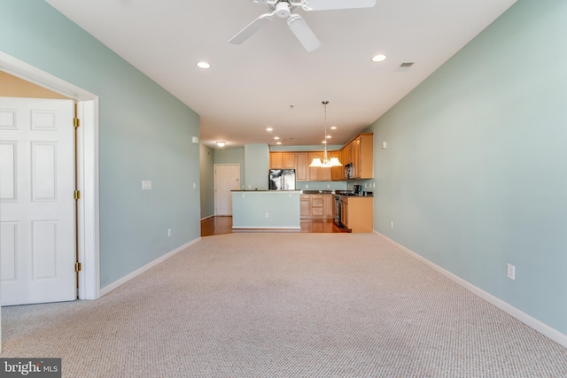 kitchen featuring black fridge, light brown cabinetry, decorative light fixtures, and light colored carpet