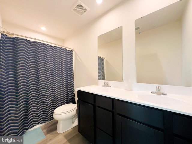 bathroom with wood-type flooring, walk in shower, vanity, and toilet