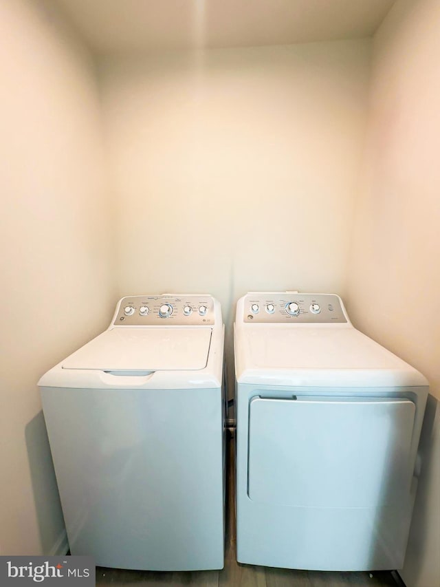 laundry area with wood-type flooring and washing machine and clothes dryer