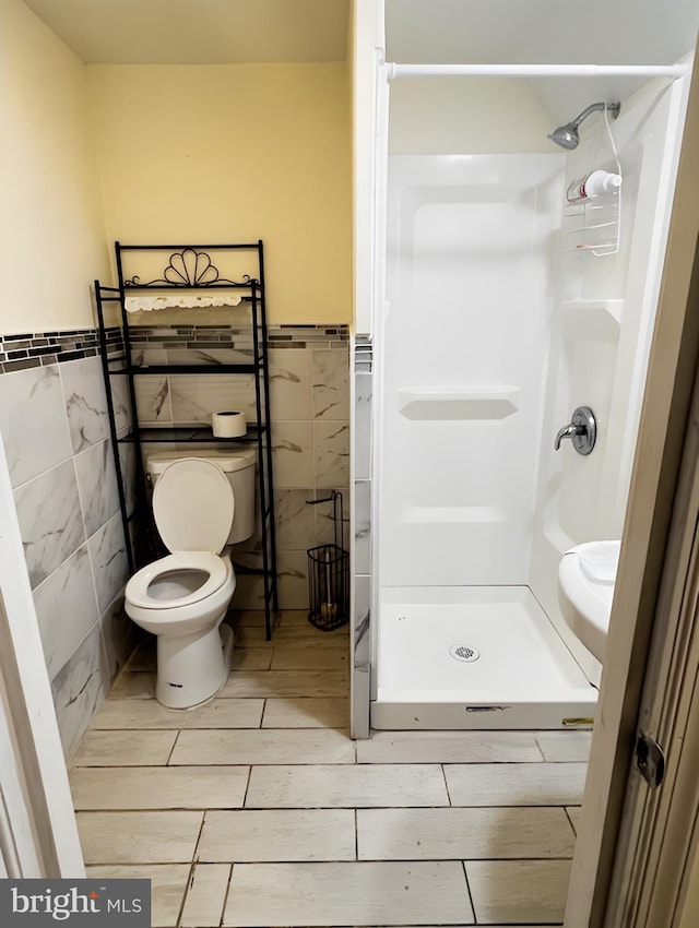 bathroom with walk in shower, tile walls, and toilet