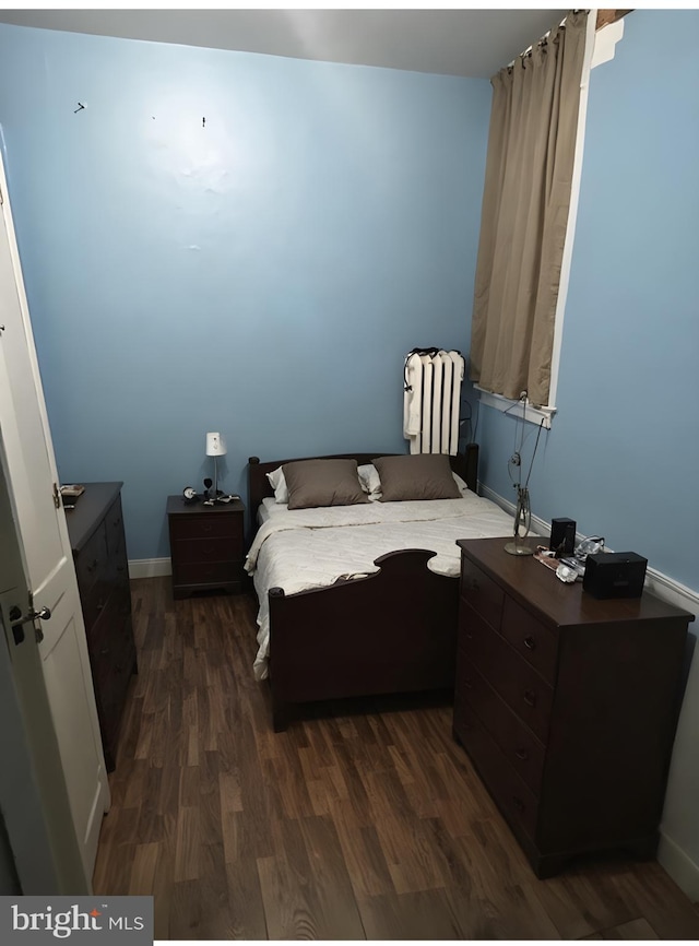 bedroom with dark hardwood / wood-style flooring and radiator heating unit