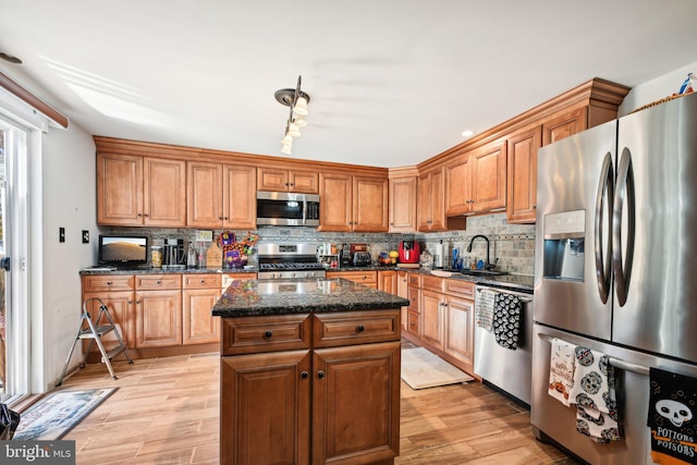 kitchen with sink, a kitchen island, appliances with stainless steel finishes, and light hardwood / wood-style floors