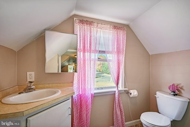 bathroom with vanity, toilet, and lofted ceiling