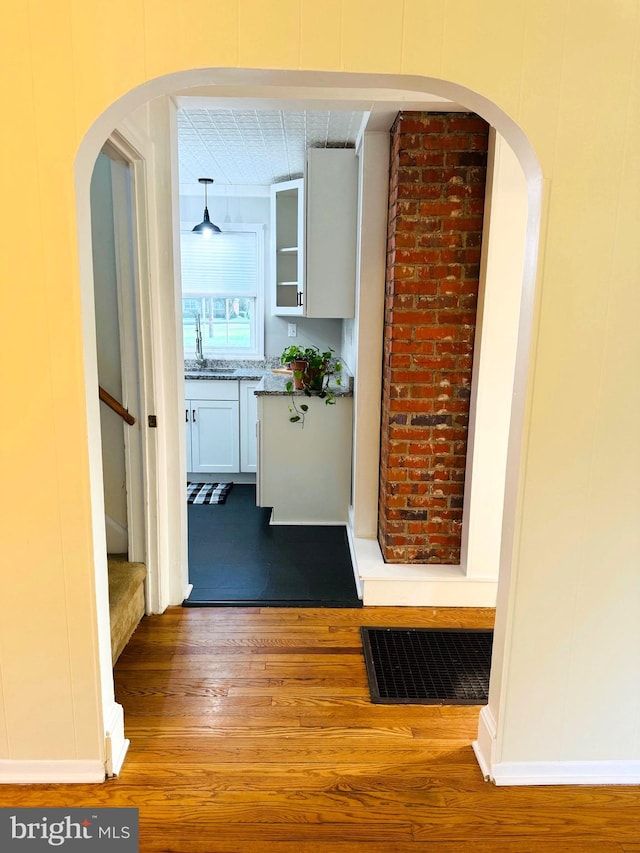 hall featuring wood-type flooring and sink