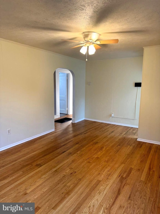 spare room with a textured ceiling, wood-type flooring, ornamental molding, and ceiling fan