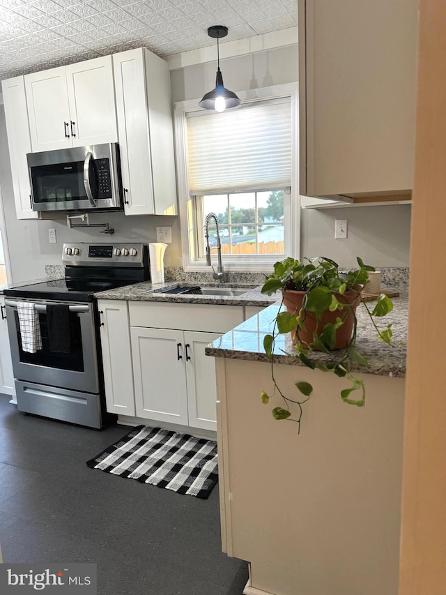 kitchen with sink, white cabinets, appliances with stainless steel finishes, decorative light fixtures, and light stone countertops