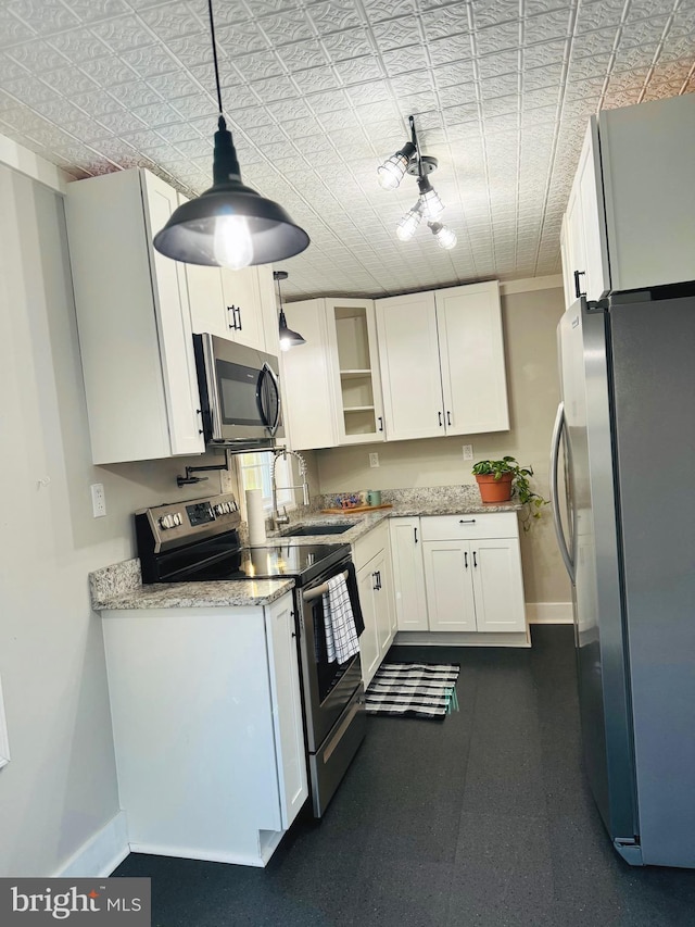 kitchen featuring pendant lighting, light stone counters, sink, white cabinets, and appliances with stainless steel finishes