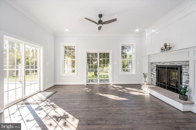 unfurnished living room featuring ceiling fan, a stone fireplace, dark hardwood / wood-style floors, and crown molding