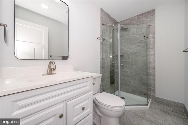 bathroom featuring vanity, toilet, a shower with door, and tile patterned floors