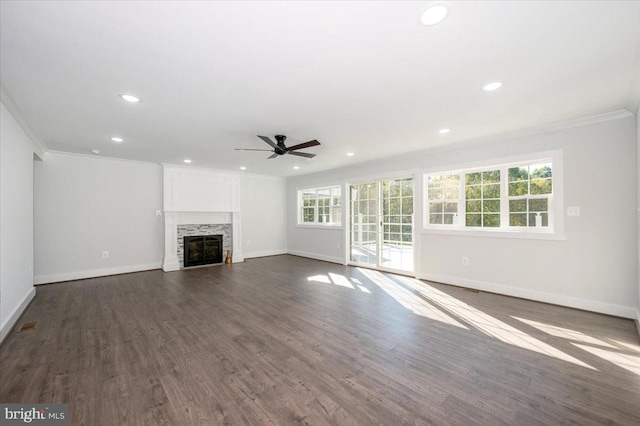 unfurnished living room featuring a fireplace, crown molding, dark hardwood / wood-style flooring, and a healthy amount of sunlight