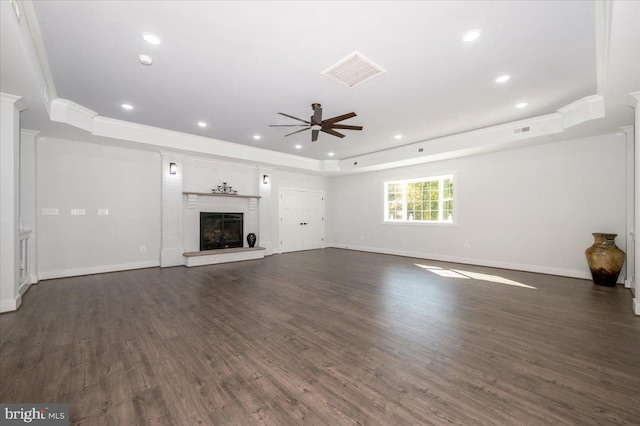 unfurnished living room with ceiling fan, a raised ceiling, dark wood-type flooring, ornate columns, and ornamental molding