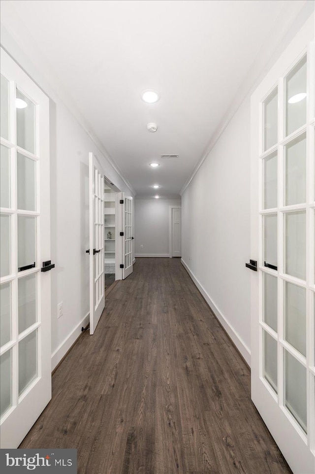 hall with dark wood-type flooring, french doors, and crown molding