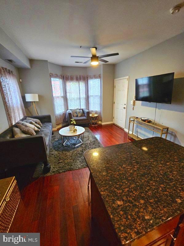 living room with dark hardwood / wood-style flooring and ceiling fan