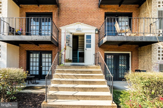 view of exterior entry featuring french doors and a balcony