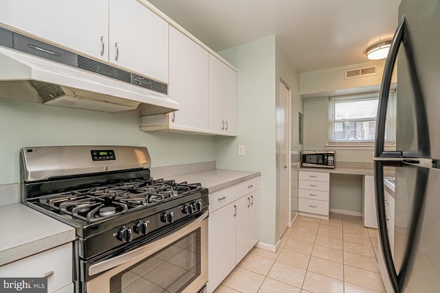 kitchen with appliances with stainless steel finishes, light tile patterned floors, and white cabinetry