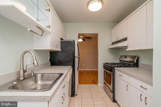 kitchen featuring light tile patterned flooring, stainless steel gas stove, sink, and white cabinetry