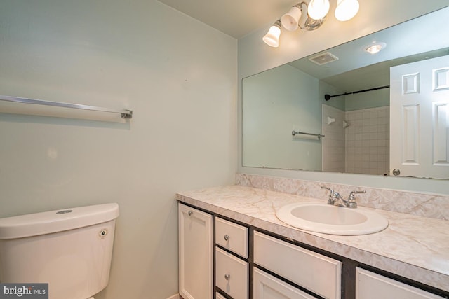 bathroom with vanity, tiled shower, and toilet