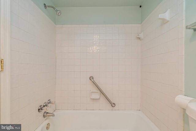 bathroom with toilet and tiled shower / bath