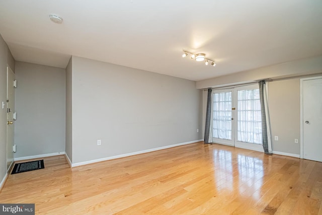 unfurnished room featuring french doors and light hardwood / wood-style flooring