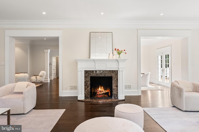 living room featuring a fireplace, ornamental molding, french doors, and hardwood / wood-style flooring