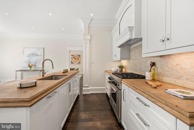 kitchen featuring white cabinets, sink, stainless steel stove, and custom range hood