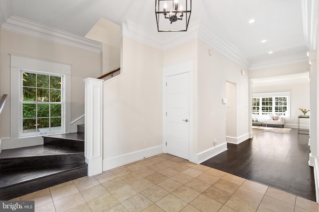 tiled foyer featuring ornamental molding and a notable chandelier